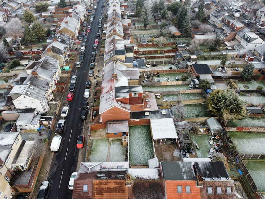 An aerial view of a residential street in Walthamstow showing closely packed terraced houses with pitched roofs, some of which are covered with a light dusting of snow, indicating winter weather. The
